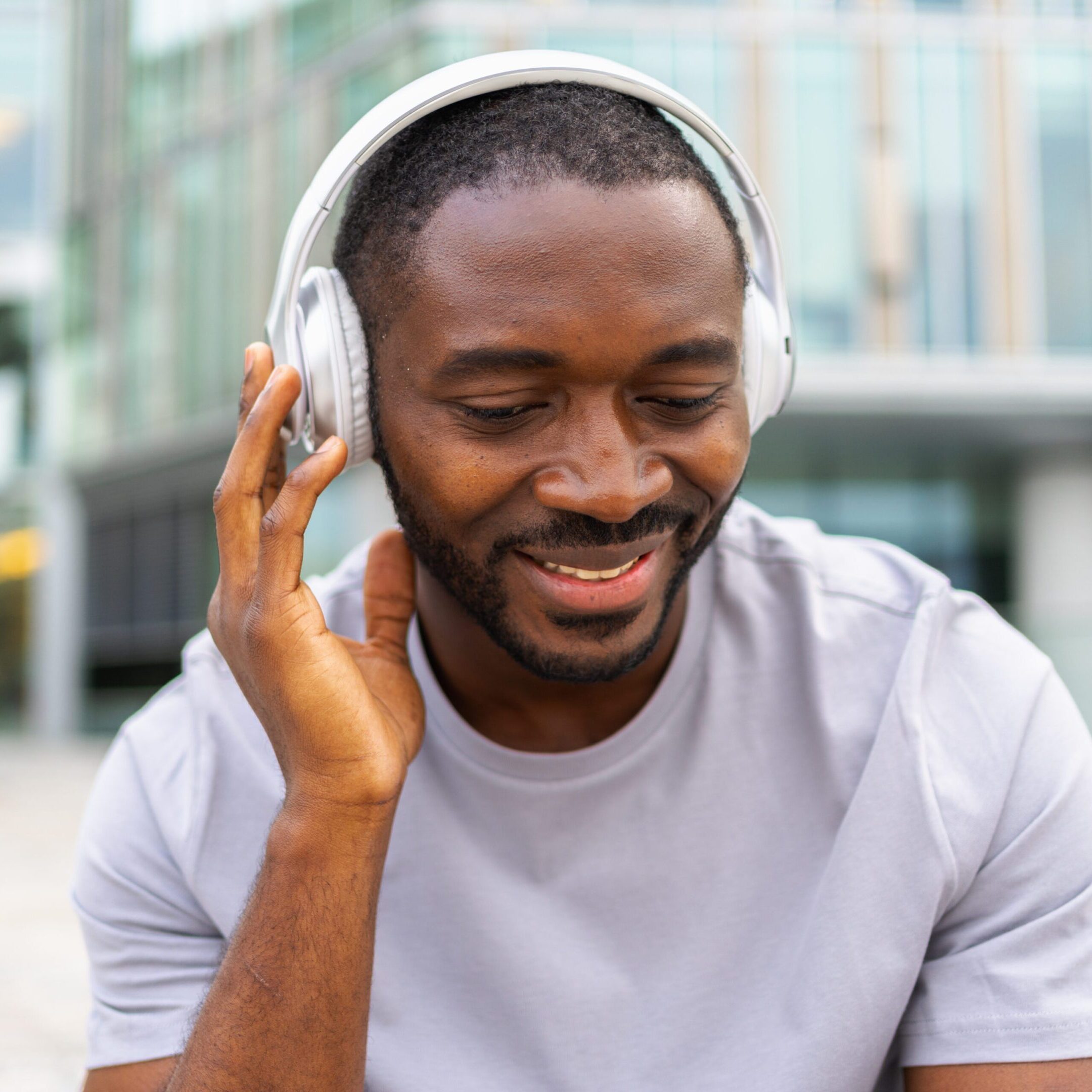 Man smiling while enjoying music with headphones outdoors.